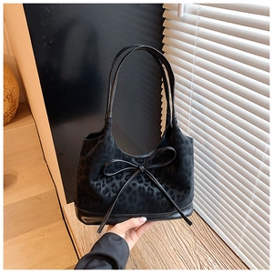 Close-up of leopard jacquard fabric and leather trim on a stylish shoulder bucket bag