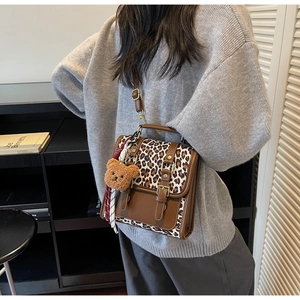 Detail of vintage brown PU leather bag with leopard print flap and plush bear charm
