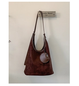 Detail view of deep brown suede hobo bag featuring a matching round coin purse charm