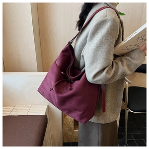 Detail of burgundy vintage tote bag with drawstring, worn with a stylish autumn outfit