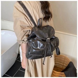 Side view of a vintage dark brown faux leather backpack with white stitching details