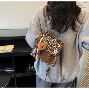 Fashionable leopard print backpack with brown leather trim and cute bear keychain detail