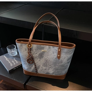 Detail of marble pattern tote bag with brown leather trim and biscuit charm pendant