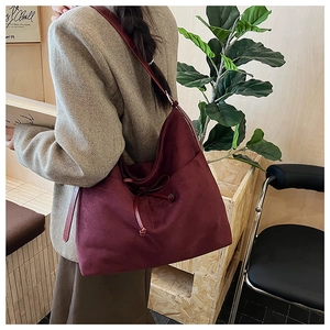 Detail of burgundy suede hobo bag featuring fine stitching and delicate leather strap