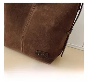Gros plan détaillé sur la texture en daim marron foncé et les coutures du sac seau