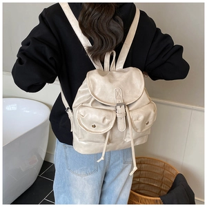 Close-up of beige leather travel backpack featuring vintage buckles and dual front pockets