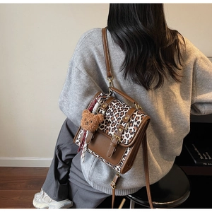 Detail of retro leopard print backpack with brown leather trim and cute plush bear charm