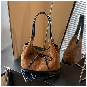 Close-up of leopard print tote bag with black leather bow detail and suede texture