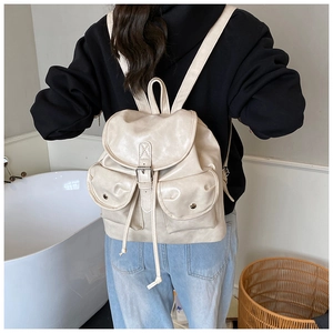 Rear view of model wearing a minimalist beige PU leather backpack with two front pockets