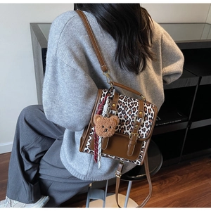 Detail view of leopard print contrast backpack with plush bear charm and vintage straps