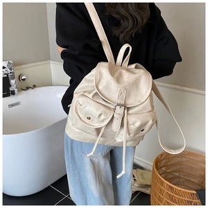 Detail of cream PU leather backpack featuring drawstring closure and retro metal buckles
