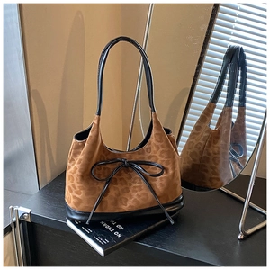 Detail view of leopard print shoulder bag with black leather bow and suede texture finish