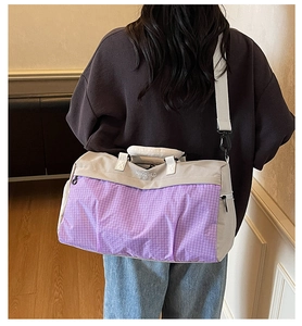 Detail showing reinforced carry handle and adjustable strap on a gray travel bag