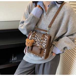 Detail view of a vintage leopard print crossbody bag with brown leather and plush bear charm