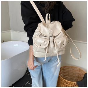 Detail of cream PU leather backpack featuring magnetic buckle pockets and drawstring closure