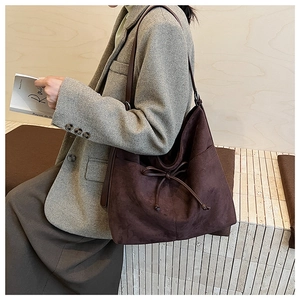 Detail of vintage dark brown suede tote bag featuring a bow drawstring and wide shoulder strap