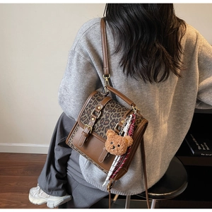 Detail of vintage leopard print backpack featuring cute bear charm and tassel detail
