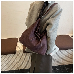 Detail view of a large vintage brown suede hobo bag with drawstring bow on a model