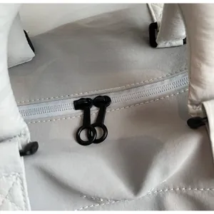 Detail of grey quilted travel bag featuring smooth dual circular zipper closures