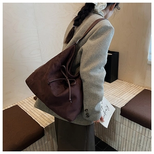 Detail of a large vintage dark brown suede tote bag with decorative bow and wide strap