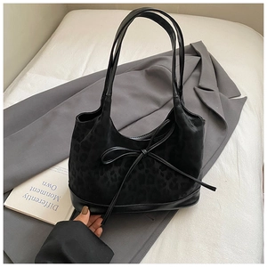 Close-up of black leopard embossed shoulder bag featuring a stylish leather bow detail