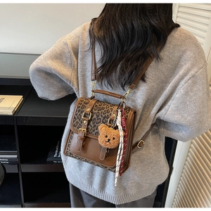 Detailed close-up of retro leopard print backpack with plush bear charm and metal buckle
