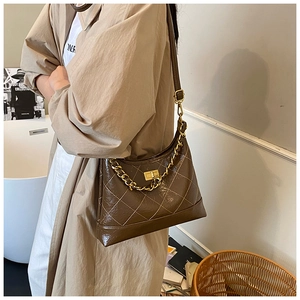 Détail d'un sac à bandoulière matelassé marron avec chaîne dorée et fermoir sur un mannequin