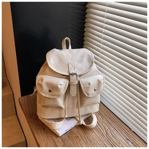 Detailed view of cream leather backpack with drawstring closure and metal buckles