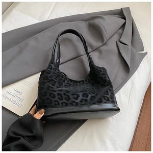 Detail of hobo bag featuring leopard print fabric with black leather straps on a grey blazer
