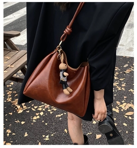 Detail of vintage brown oil wax leather tote bag with a decorative bunny pendant