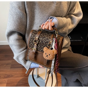 Detail of vintage leopard print backpack with brown leather straps and plush bear charm