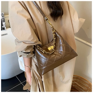 Détail du sac matelassé marron foncé avec chaîne dorée et fermoir rotatif métallique