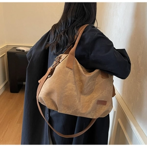 Detail of large khaki tote bag with wide shoulder strap and leather patch detail