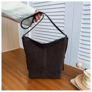 Détail du sac seau en daim avec bordure en cuir noir et bandoulière réglable