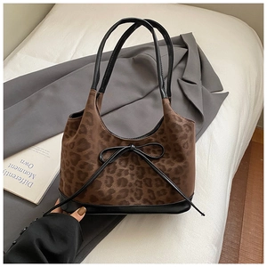 Close-up of leopard print shoulder bag with black leather bow detail on a white bed