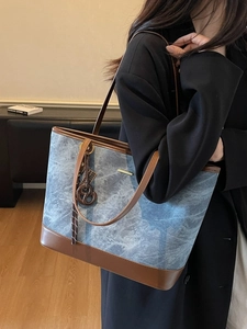 Minimalist blue-grey denim tote bag with brown leather trim and metallic gold bar detail
