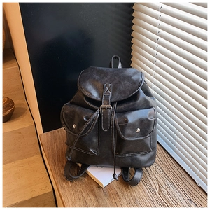 Detail of dark grey retro backpack showing vintage leather texture and buckle pockets