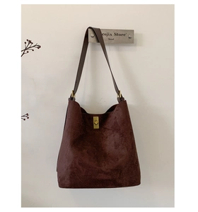 Detail of dark brown suede hobo bag featuring a gold rectangular twist lock closure