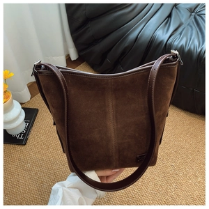Détail du cabas en daim marron foncé avec coutures verticales et bandoulière réglable