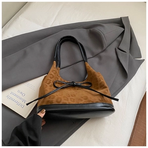 Detail of leopard print bucket bag with black leather trim and bow on gray blazer