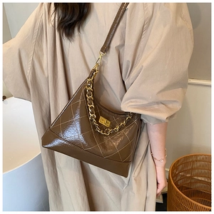 Détail du sac bandoulière matelassé marron foncé avec finition brillante et chaîne dorée