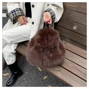Detail of dark brown faux fox fur backpack with drawstring closure and silver hardware