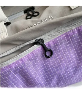 Close-up of durable gray nylon and purple ripstop fabric with a matte ring zipper pull