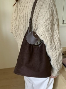 Large brown suede hobo bag with round charm and soft texture for minimalist casual look