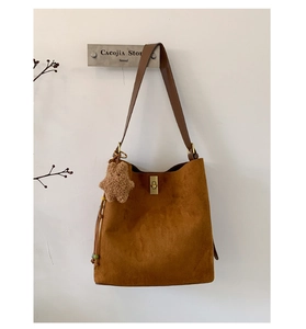 Detail of caramel suede tote bag featuring a gold metal lock and star-shaped plush charm