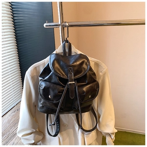 Detail view of vintage black leather backpack with white stitching and metal buckle accents