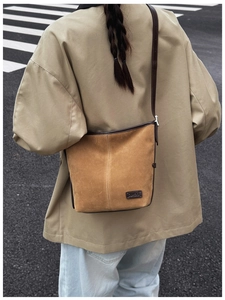 Détail du sac seau en daim marron avec bordure en cuir et bandoulière réglable