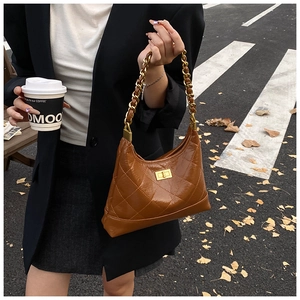 Détail du sac hobo matelassé caramel avec poignée en chaîne dorée et fermoir pivotant