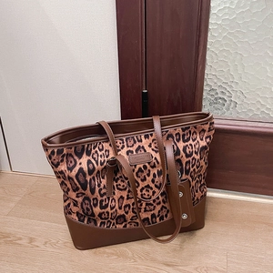 Detail view of leopard print tote bag with brown leather trim and logo patch