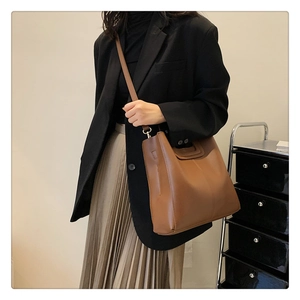 Brown vintage large capacity tote bag styled with a black blazer and pleated skirt